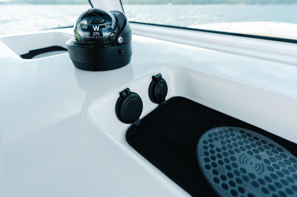 Compass, cleats, and non-skid mat on white helm console with ocean in background