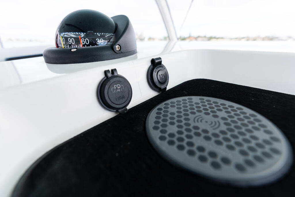 Boat helm electronics including compass, USB ports, and speaker system mounted on white console