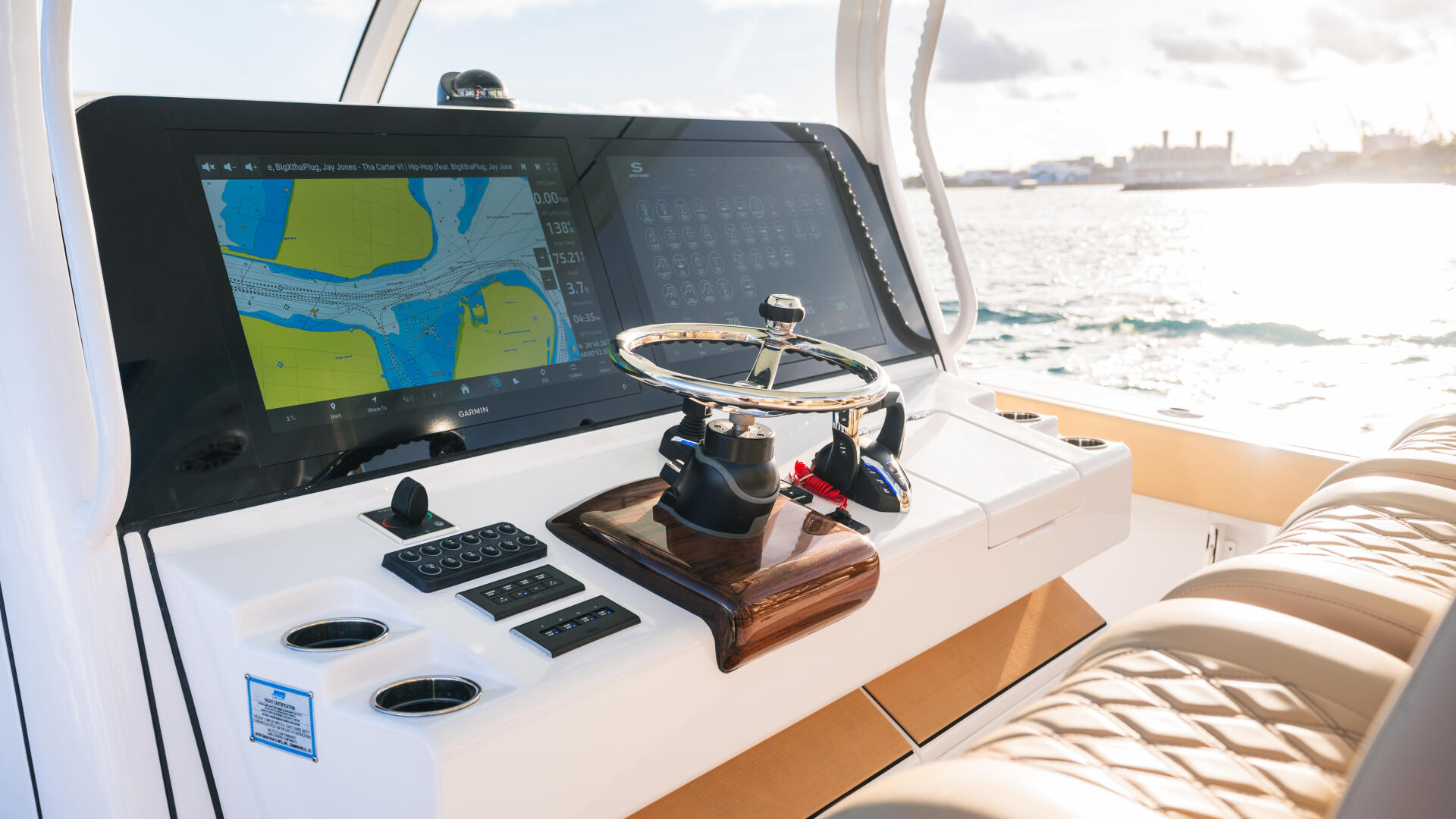 Helm console with dual Garmin chartplotters, Edson steering wheel, and control panels overlooking open water
