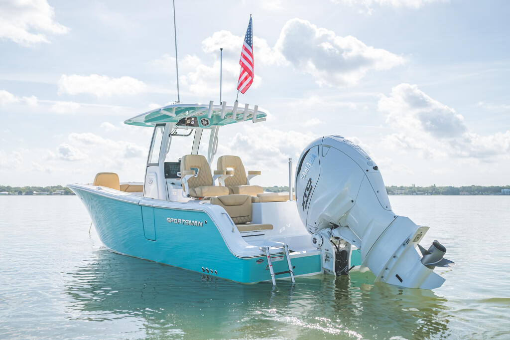 Turquoise and white center console boat with hard-top anchored in shallow water flying American flag