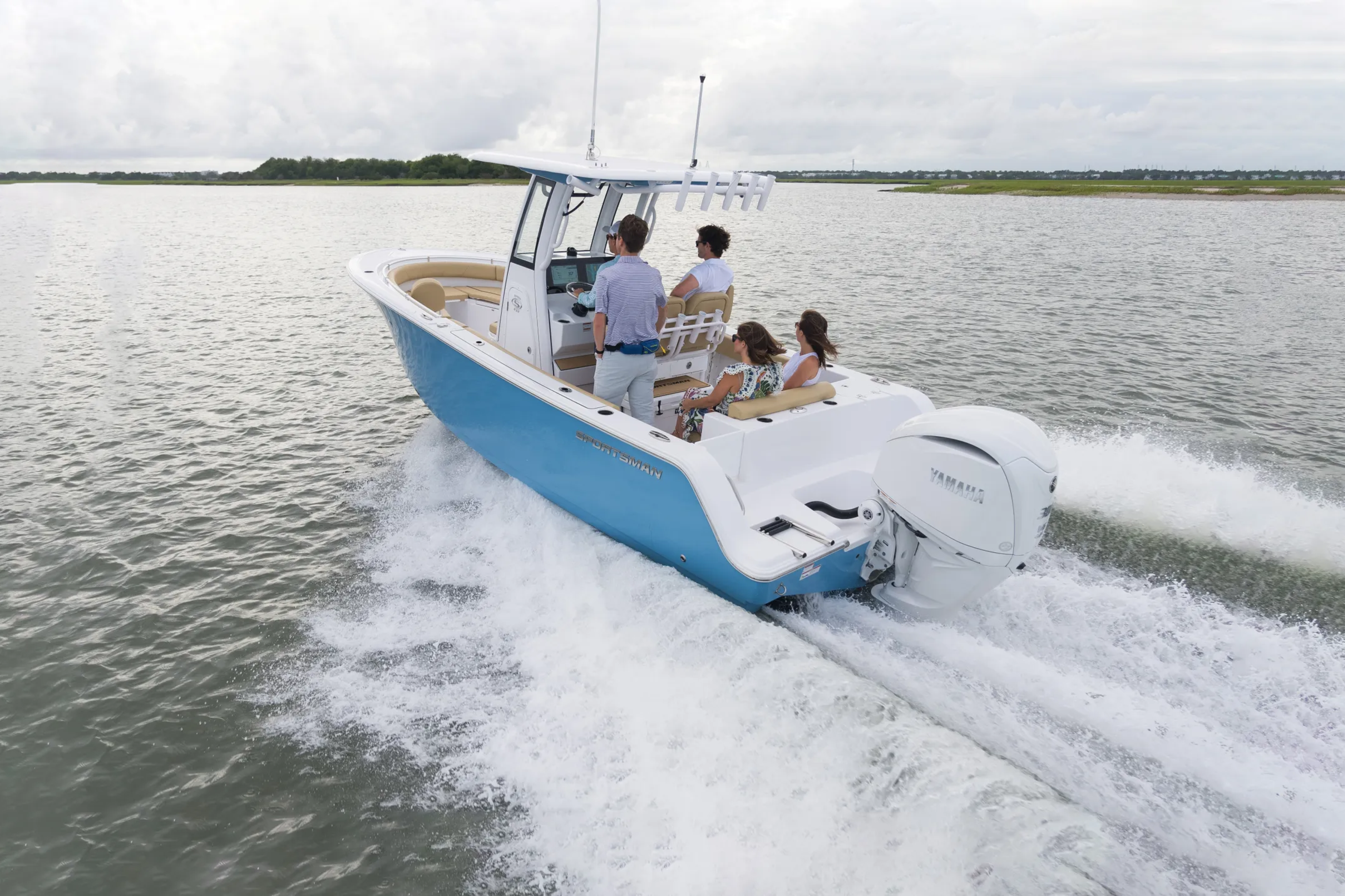 Family of four cruising in blue and white center console boat through shallow coastal waters