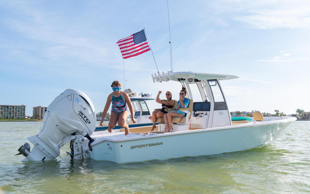 Family enjoying a Sportsman bay boat anchored in shallow sandbar waters with American flag flying