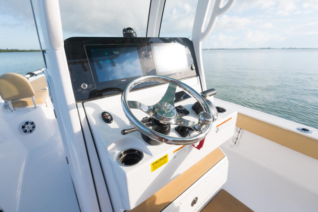 Helm station with stainless steel wheel, digital display, and calm water ahead