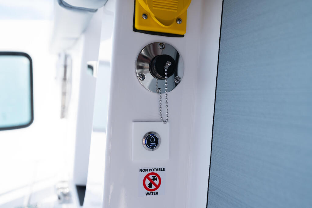 Boat interior wall showing yellow horn, key ignition with chain pull, water outlet button, and non-potable water warning label