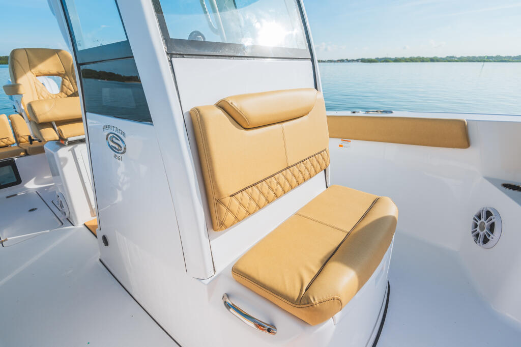 Tan leather seating and windshield of Heritage 261 center console boat with calm water and shoreline in background