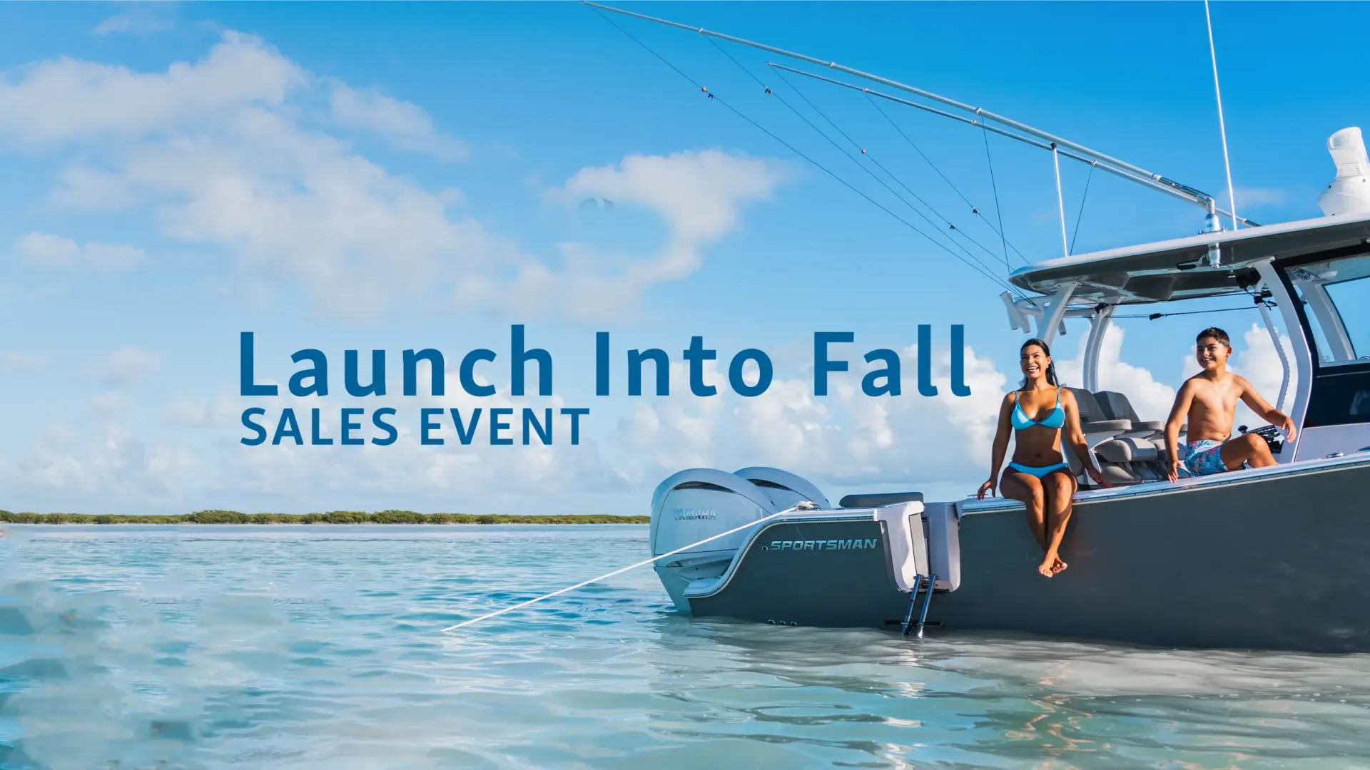 Two people in swimwear sit on the gunwale of a Sportsman boat docked in shallow turquoise water under clear skies