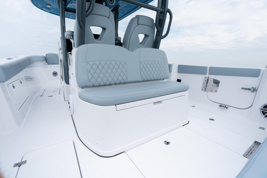 Gray and white boat helm with dual captain's chairs, windshield, and control panel under a hard-top canopy