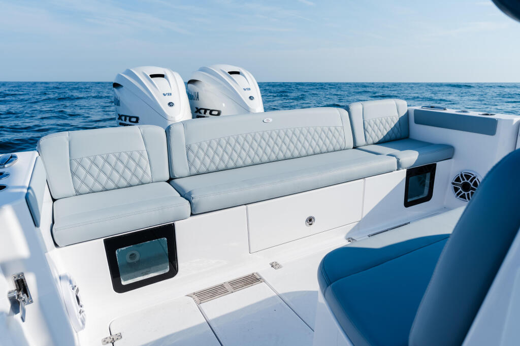 Spacious cockpit with quilted white seating, dual outboard engines, and electronics on calm blue water