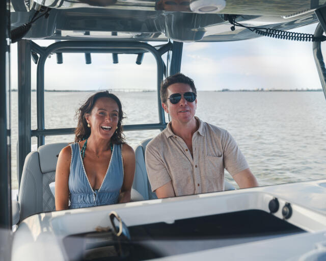 Couple smiling together inside a center console boat with water views behind them