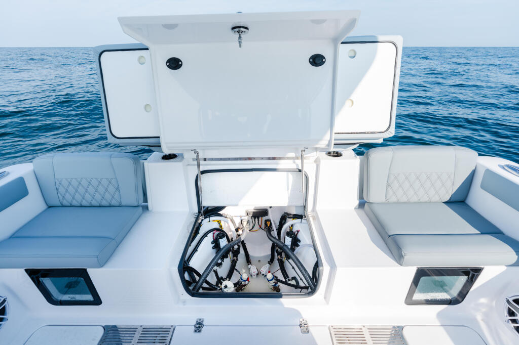 Overhead view of boat cockpit with open engine hatch, dual seating, and control electronics