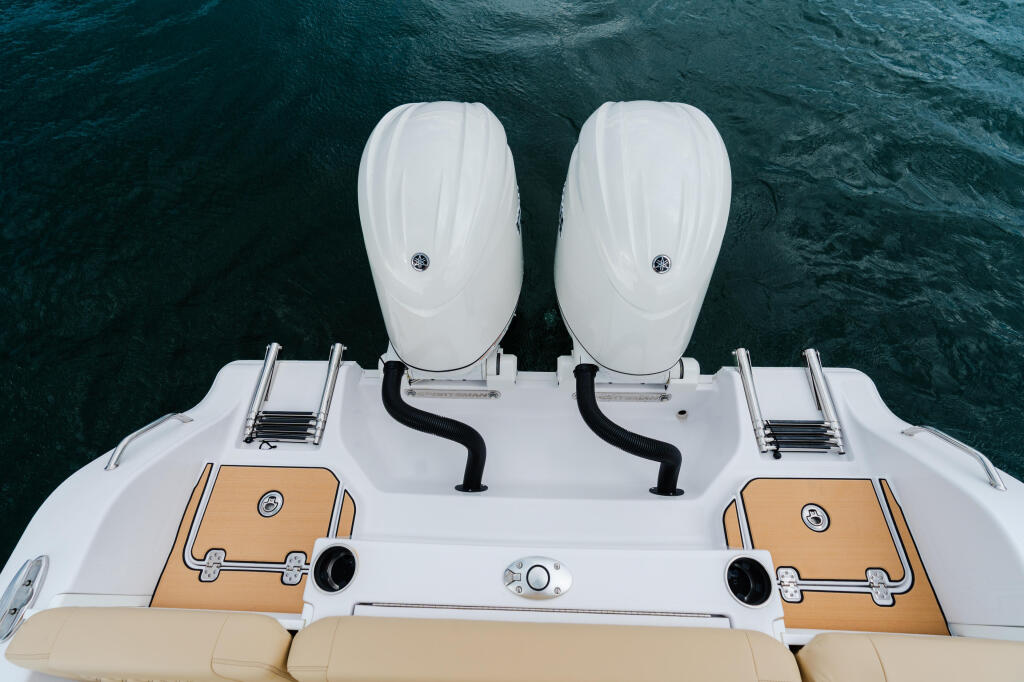 Overhead view of a dual-console boat with twin outboard engines and teak accents in blue water