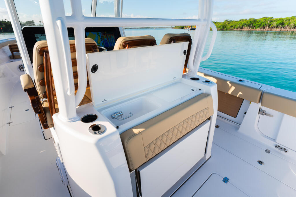 Open center console with tan upholstered seating, storage compartments, and hard-top overlooking turquoise water and mangroves
