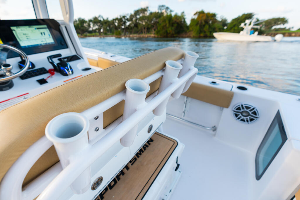 Center console helm station with GPS electronics, cup holders, and tan upholstery overlooking calm water