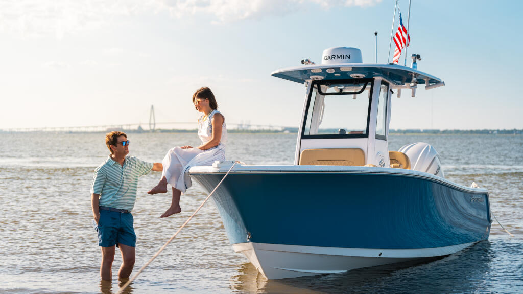 Family wading in shallow water next to a blue and white center console boat with Garmin electronics and American flag