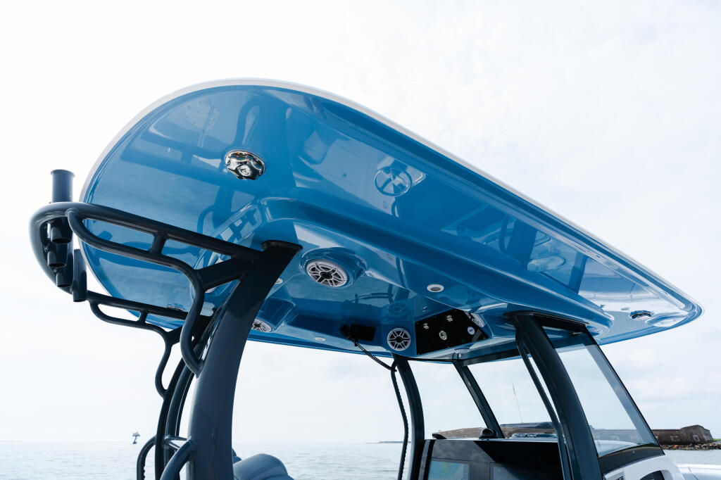 Blue hard-top boat with electronics and helm visible under the canopy, anchored on calm water