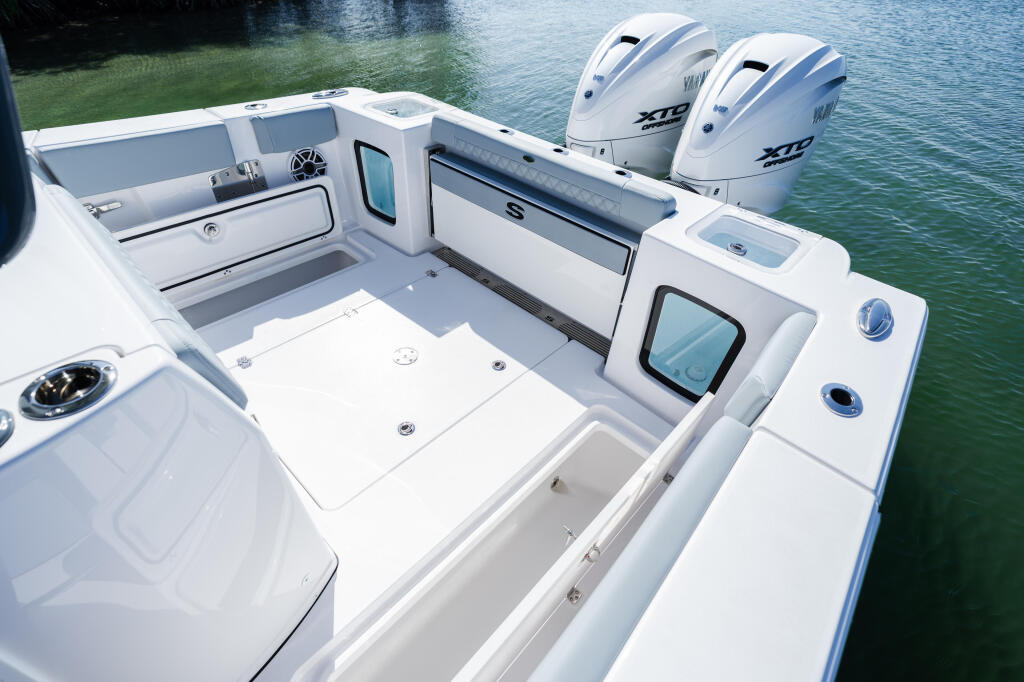 Open 322 boat cockpit with dual outboard engines, gray seating, and storage compartments alongside dock
