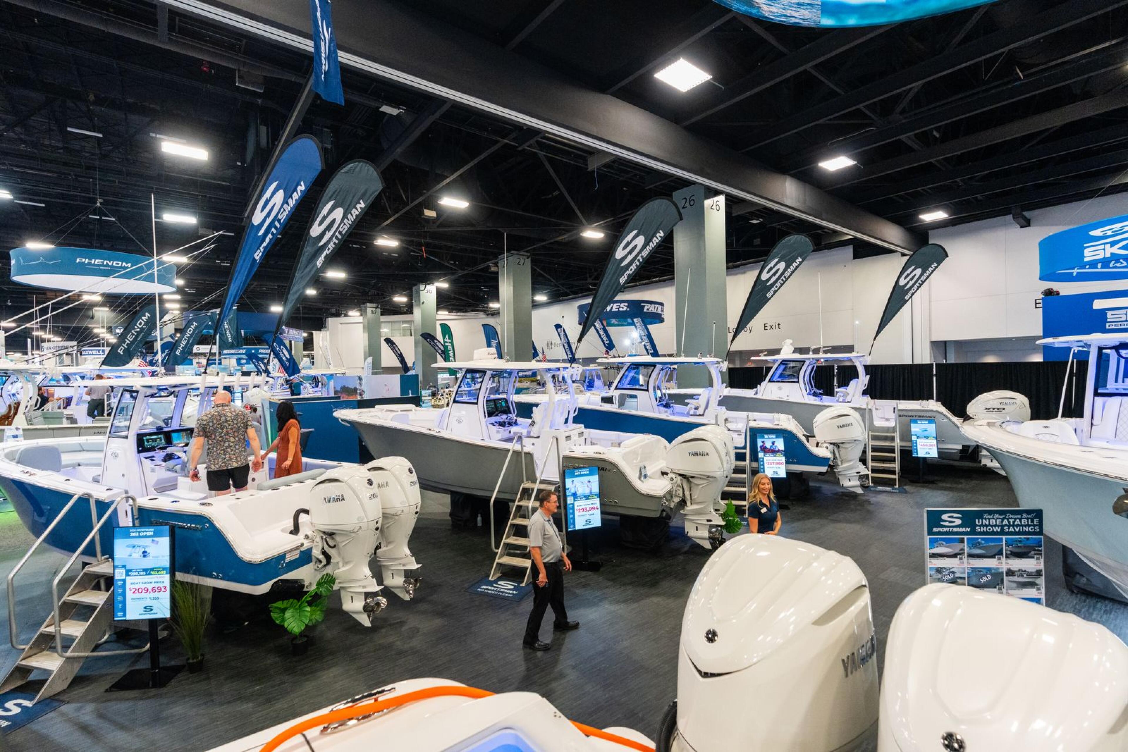 Indoor boat show display with multiple blue and white boats featuring Yamaha engines under bright ceiling lights