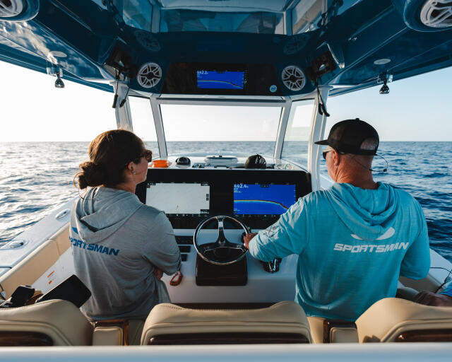Two anglers at the helm monitoring GPS and fish-finder displays while cruising offshore