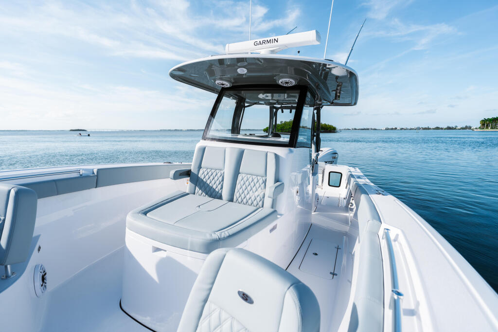 White center console fishing boat with Garmin hard-top cruising through calm turquoise water under clear blue sky