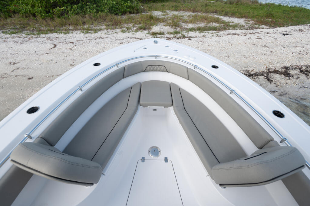 Center console boat beached on sandbar with gray upholstered seating and white hull viewed from bow
