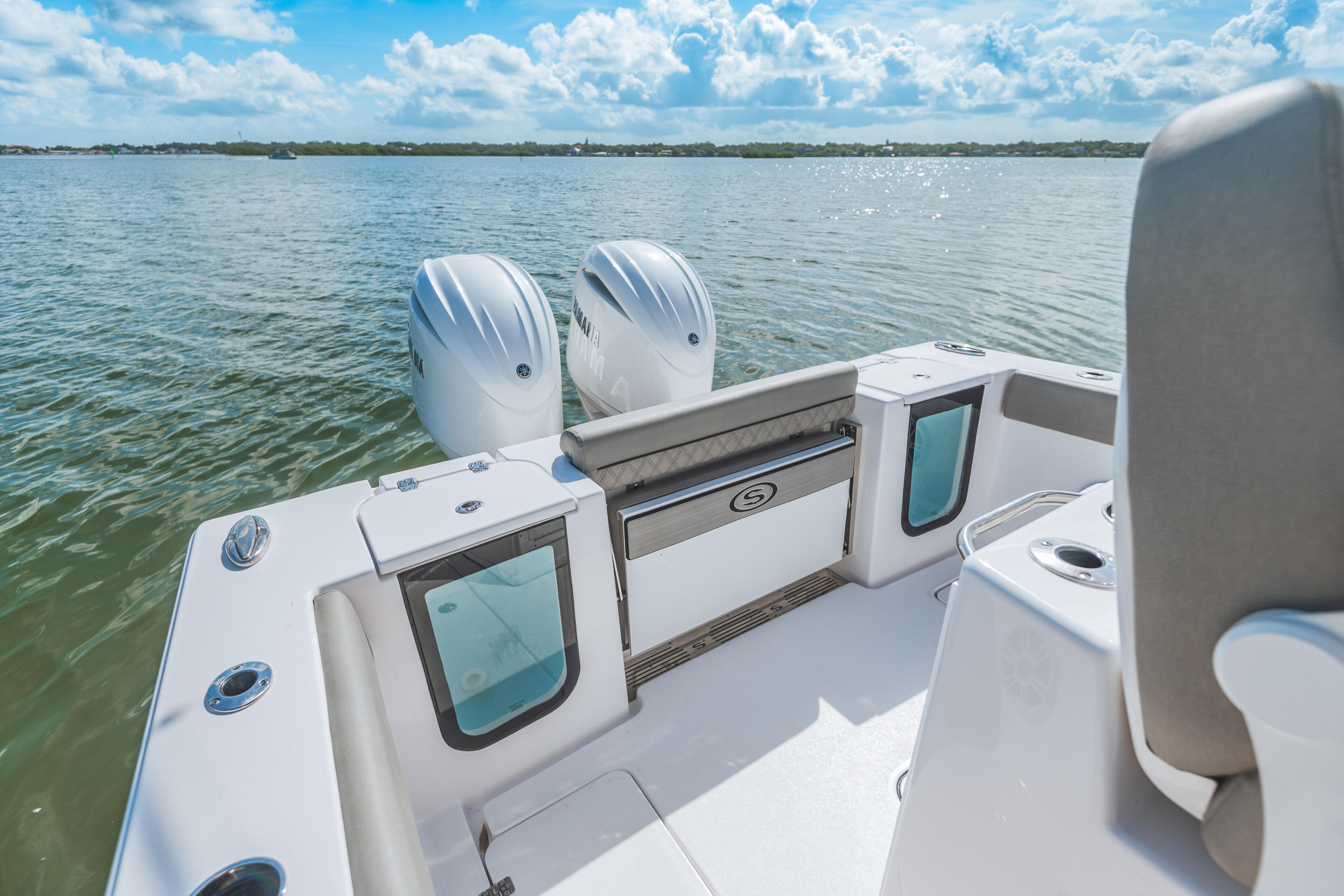 Dual outboard engines and helm station visible on a white center console boat anchored in calm turquoise water