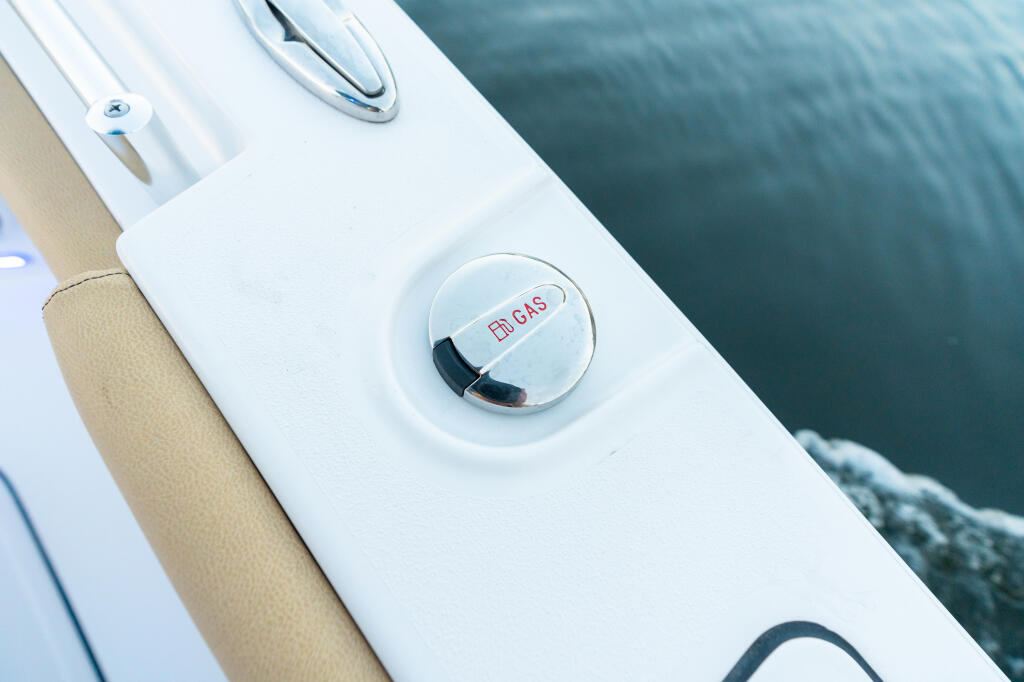 Dual fuel fill caps on white boat hull next to calm water