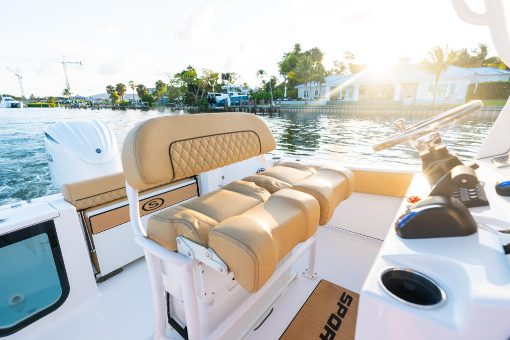 Tan leather seating and console detail on center console boat docked at marina with waterfront homes visible