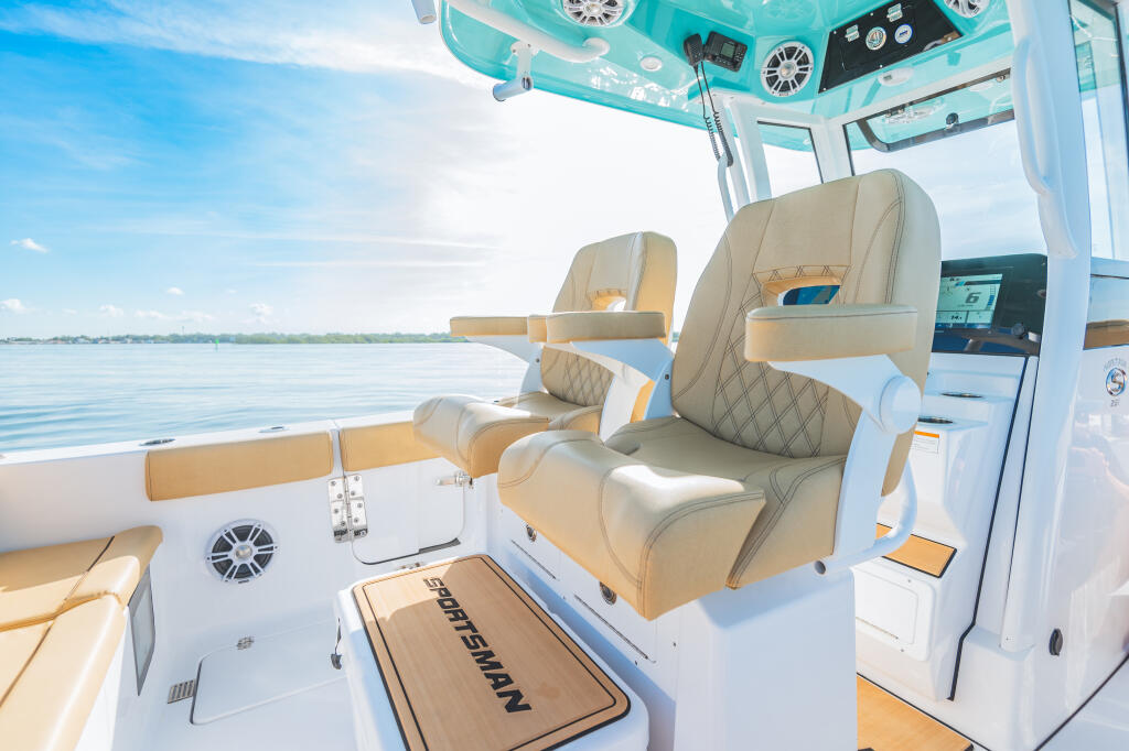 Helm area with tan upholstered captain's chairs and turquoise hardtop, overlooking calm water