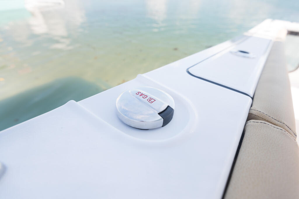 Dual fuel fill cap mounted on the white console of a center console boat with clear turquoise water visible below