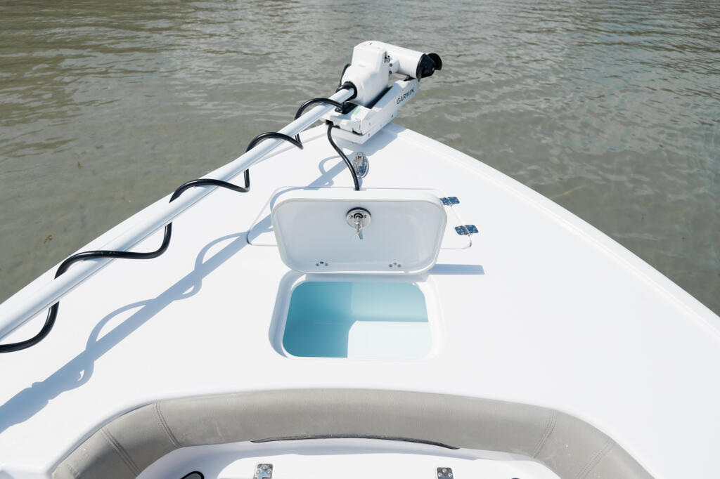 White fishing boat bow with open livewell and twin engines viewed from above on calm water