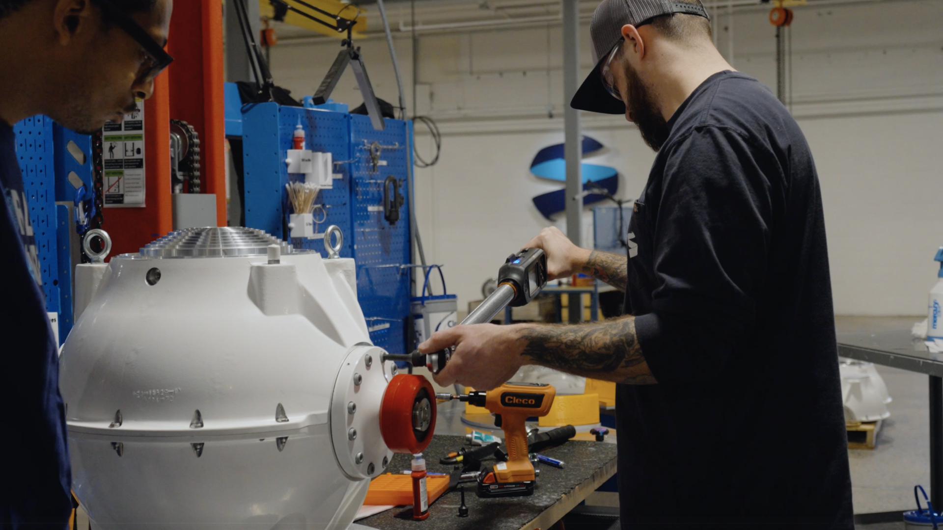Technicians working on a marine engine component in a workshop facility