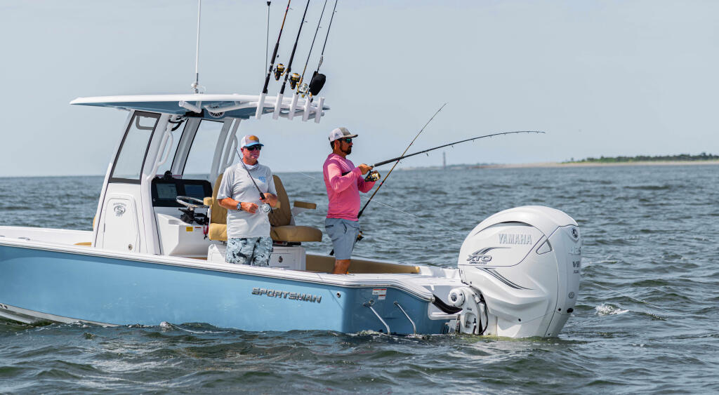 Two anglers fishing from a center console boat with rod holders and Yamaha engine in calm coastal waters