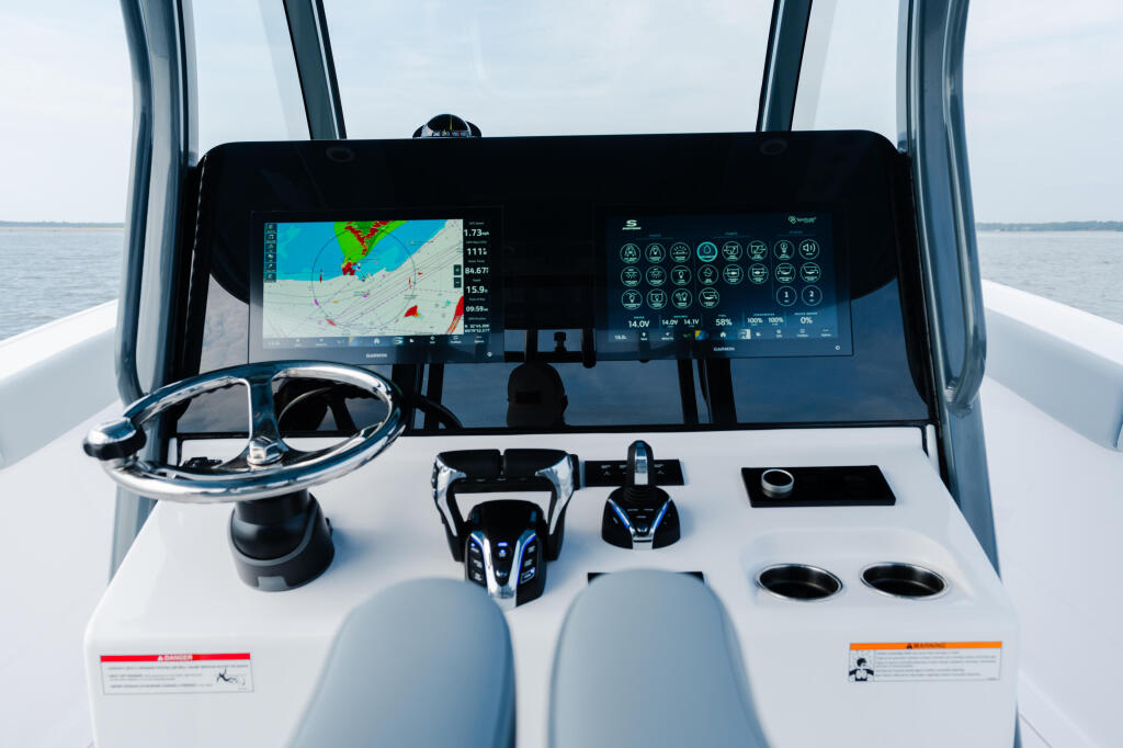 Modern boat helm with dual displays showing navigation charts, controls, and instrument gauges