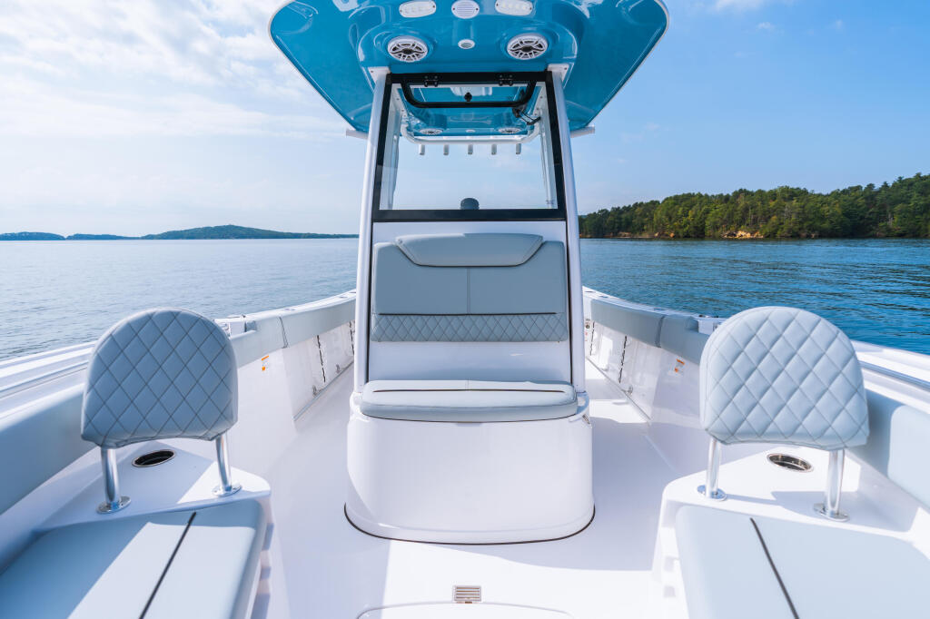 Center console boat helm and forward seating with blue hard-top canopy on calm lake waters