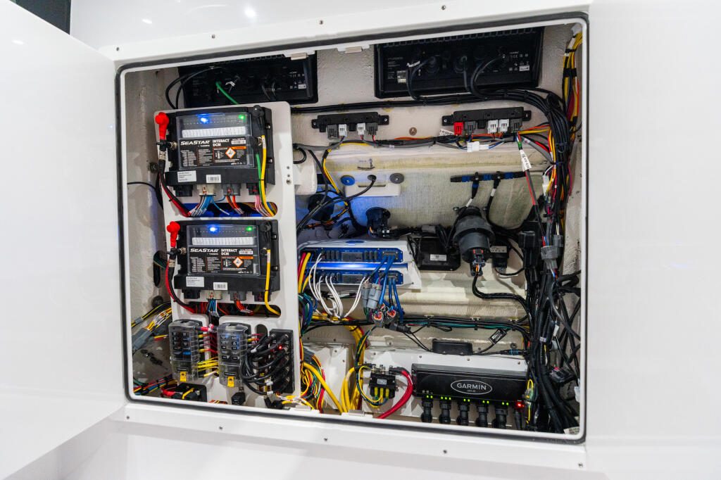 Boat electrical panel showing dual battery systems, fuse boxes, Garmin display, and color-coded wiring harnesses