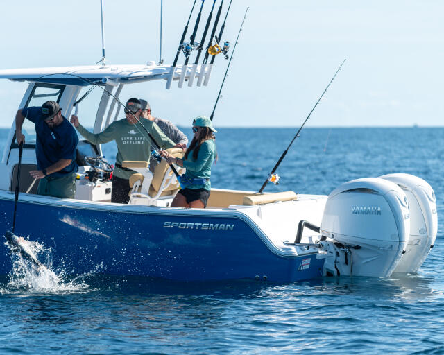 Anglers fish from offshore charter boat with multiple rod holders and outboard engine visible