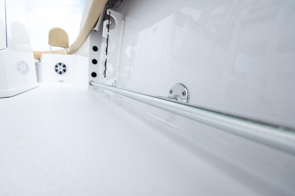 Clean white cabin interior with tan seating, ventilation fan, and aluminum toe rail along the wall
