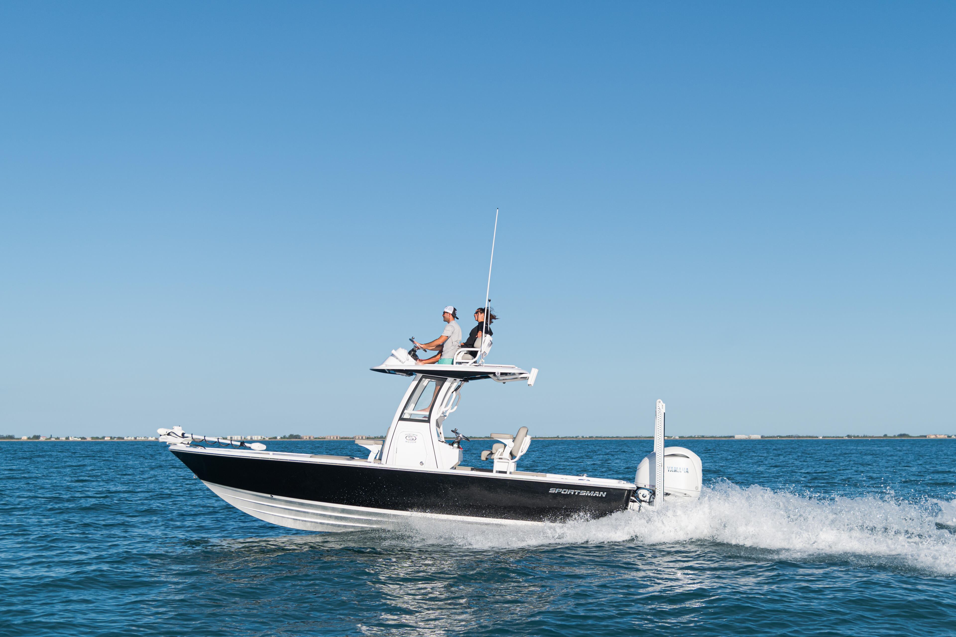 Sportsman boat running offshore in clear blue water with two people at the elevated helm station