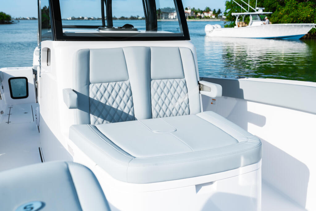 Luxurious white cabin seating with quilted blue accents and convertible cushioning in a modern center console boat
