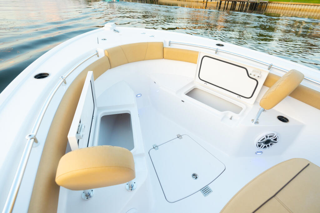 Spacious open bow seating area with tan cushions, storage hatch, and helm window on a center console boat