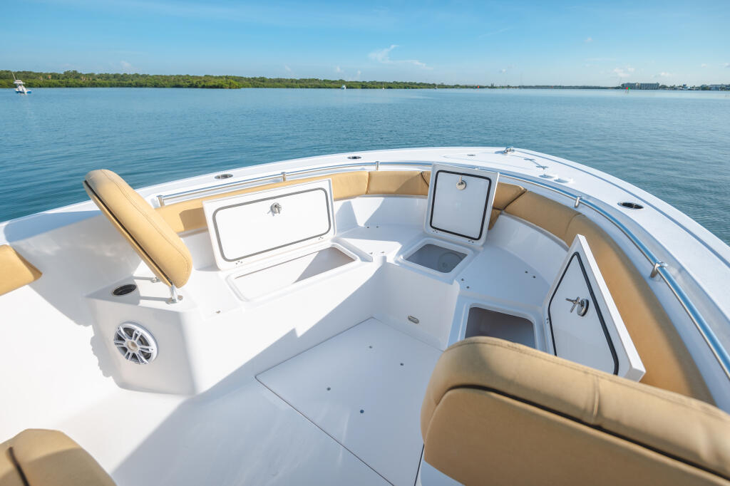 Heritage 261 center console boat showing tan seating, white deck, and storage compartments with calm water and shoreline in background