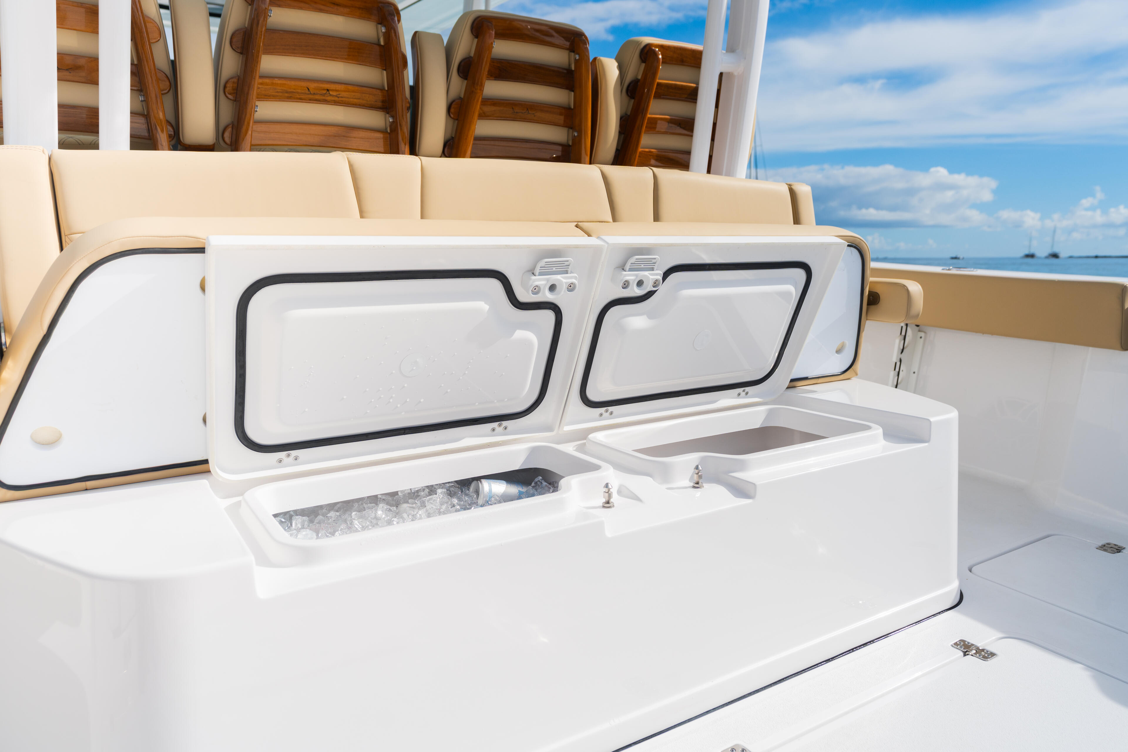Open coolers with ice and storage compartments on a boat deck overlooking the ocean