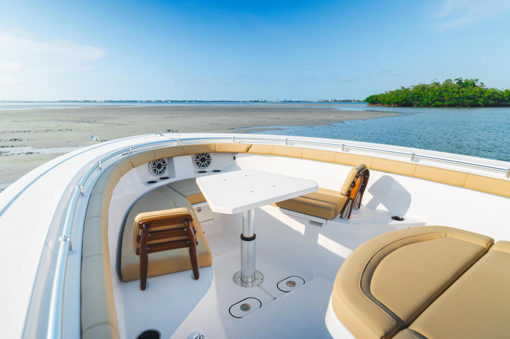 Spacious deck of a center console boat with tan seating, white flooring, and mangrove shoreline beyond