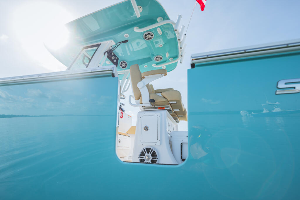 Overhead view of center console boat showing hard-top with electronics, helm station, and turquoise hull in calm water