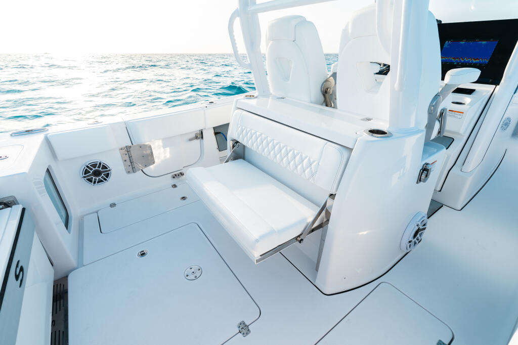 Spacious helm area with white fiberglass leaning post, rear-facing seating, and integrated sink overlooking open ocean