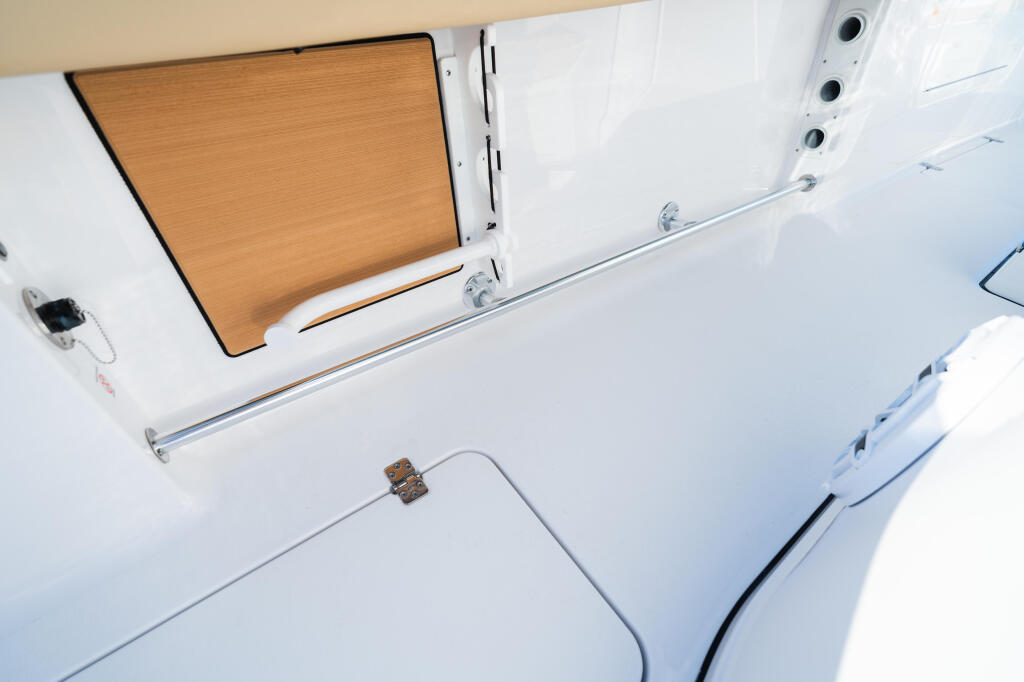 Overhead view of boat's white interior with wooden hatch cover and ventilation vents