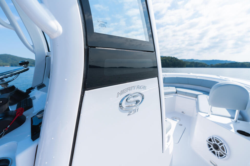 Heritage 231 center console boat with open cabin door on calm lake with forested shoreline