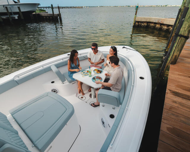 Four friends enjoying dinner together in a white center console boat docked at a marina