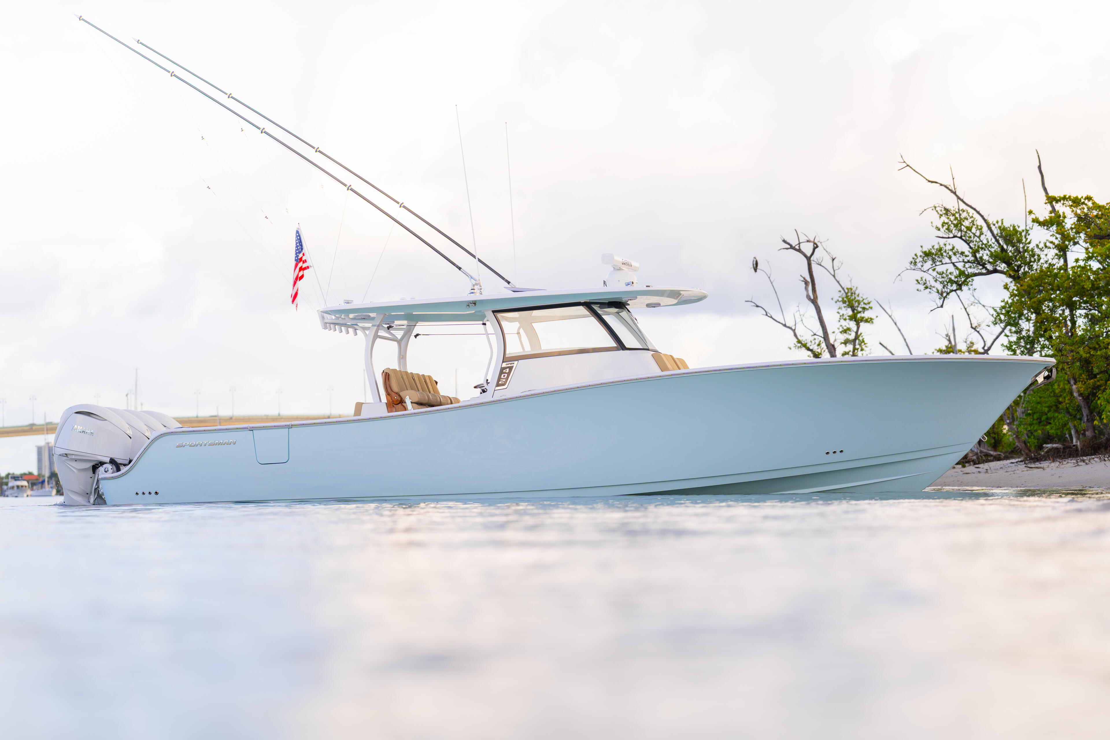 Light blue center console boat beached on sand with American flag and hardtop canopy