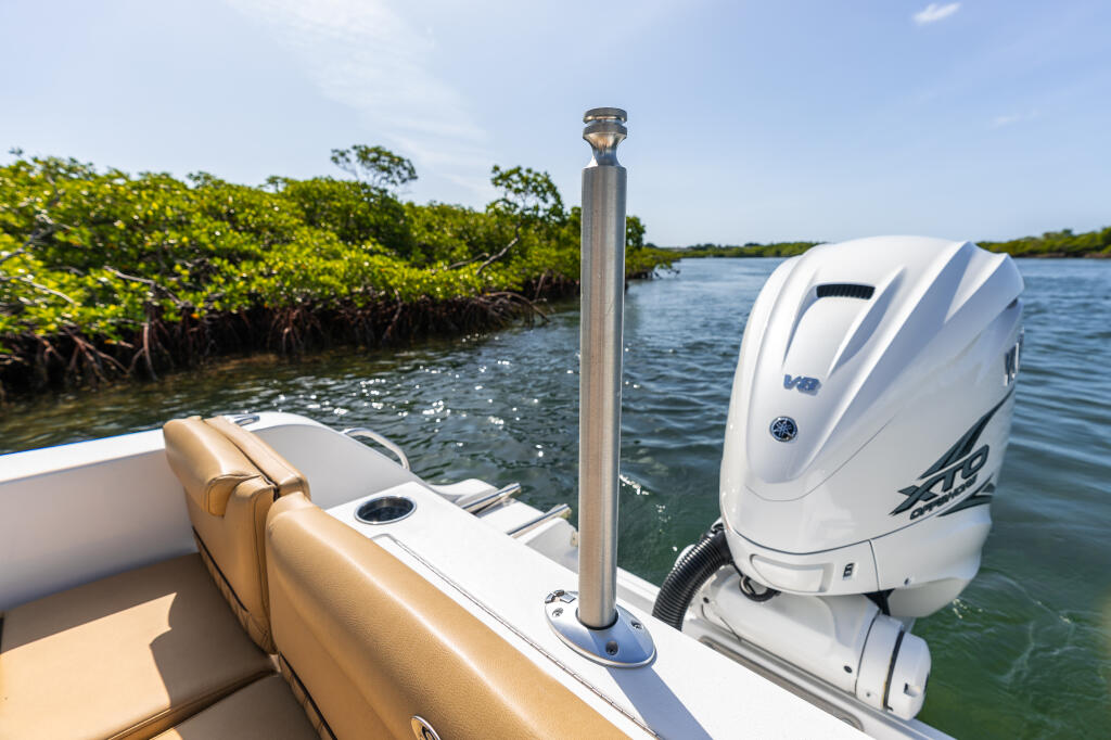 White boat with tan seating anchored near mangrove shoreline with white outboard engine mounted on transom